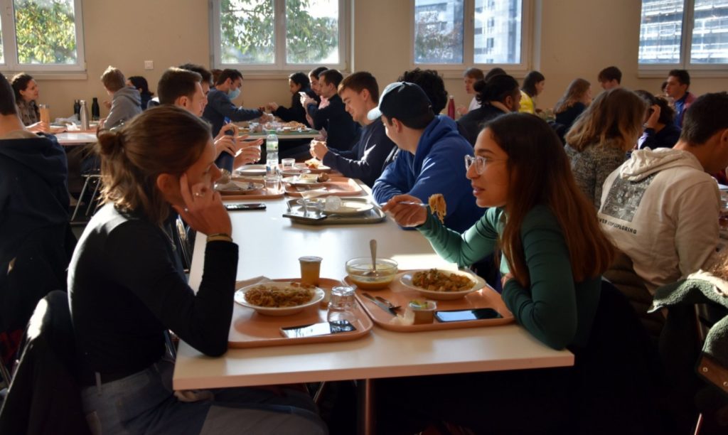 Deux étudiantes discutent en dégustant un pad thaï végétal