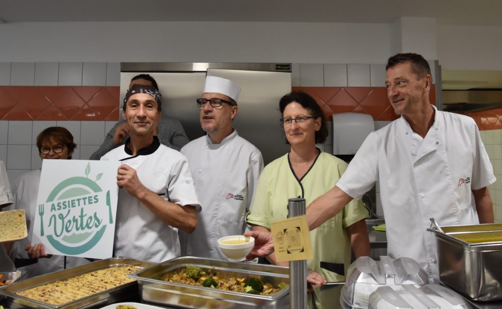 Le chef et son équipe de cuisine posent avec le label Assiettes Vertes devant les plats d'origine végétale du jour